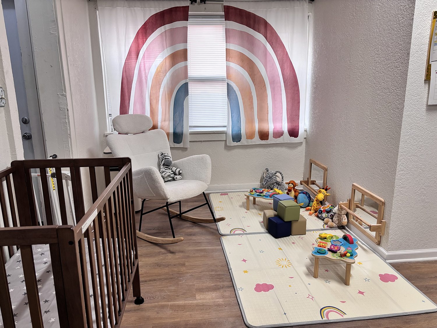 The ECU infant nook with a rocking chair, soft blocks and floor mats under a rainbow window