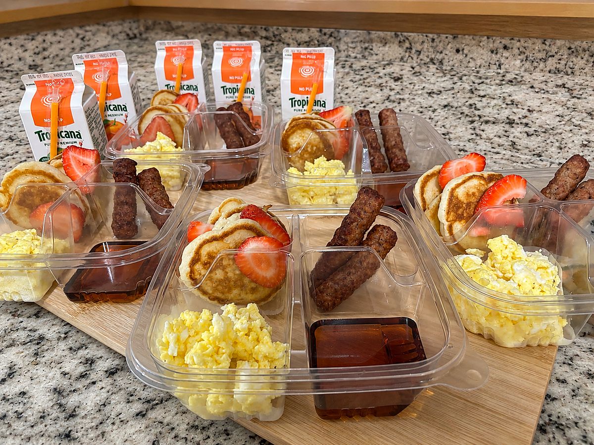 Breakfast trays with pancakes, scrambled egg, sausage, strawberries and orange juice