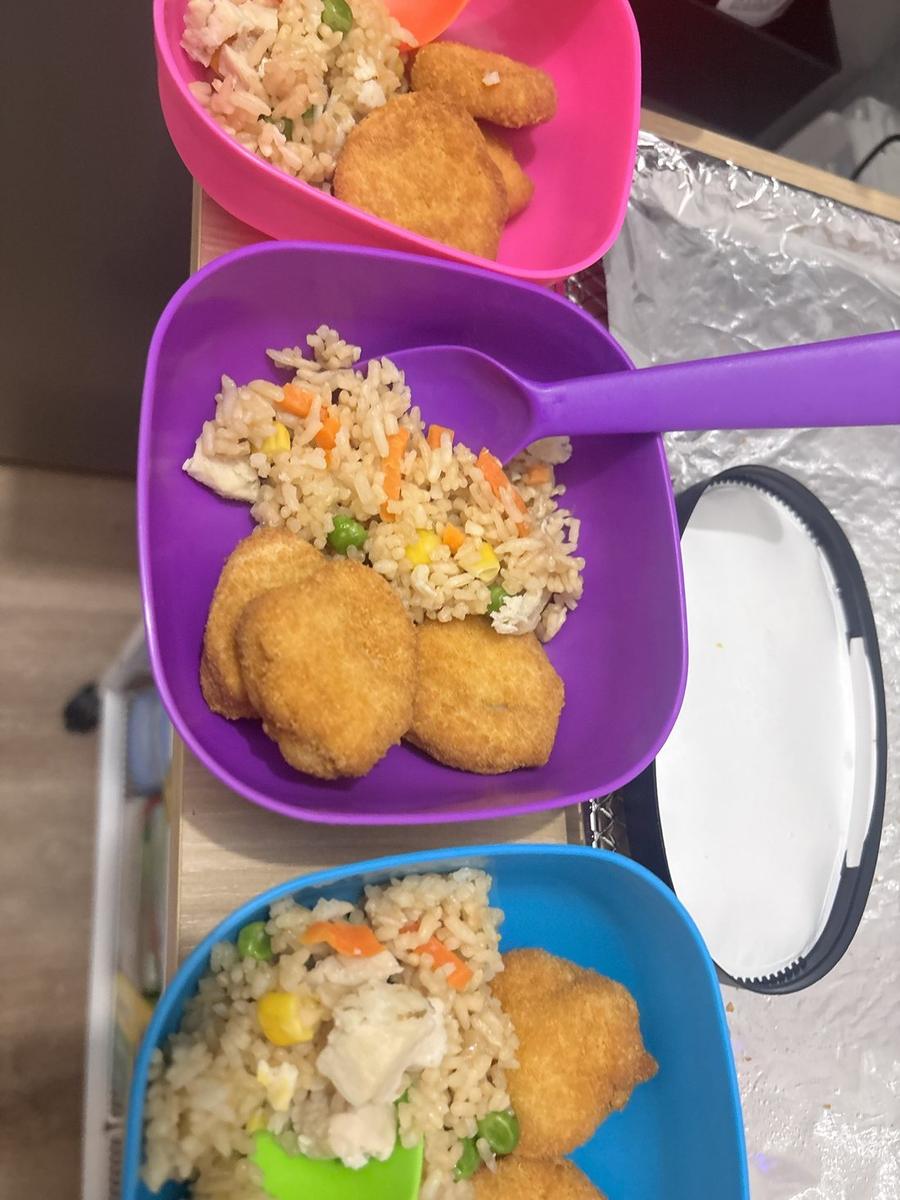 Chicken fried rice with vegetables and baked nuggets in children's bowls